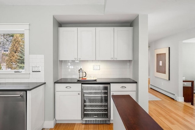 kitchen featuring dark countertops, light wood-style flooring, wine cooler, and a baseboard heating unit