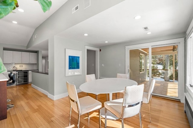 dining area with light wood finished floors, baseboards, wine cooler, and visible vents