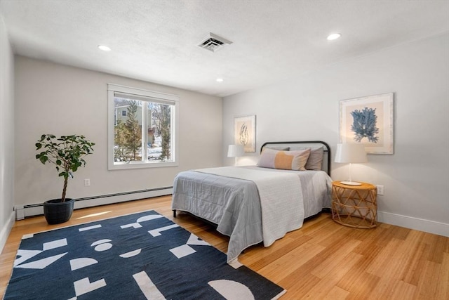 bedroom with recessed lighting, visible vents, light wood-style floors, a baseboard heating unit, and baseboards