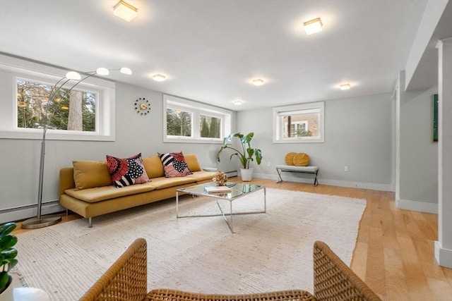 living room featuring light wood-type flooring, baseboards, a baseboard heating unit, and a baseboard radiator