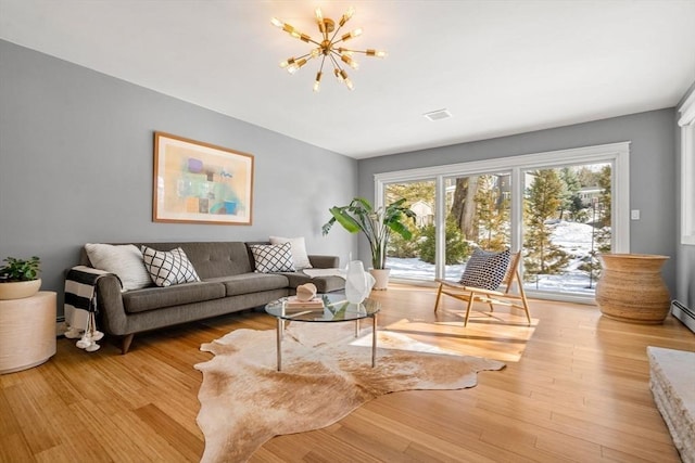 living area with a chandelier, light wood-type flooring, and visible vents