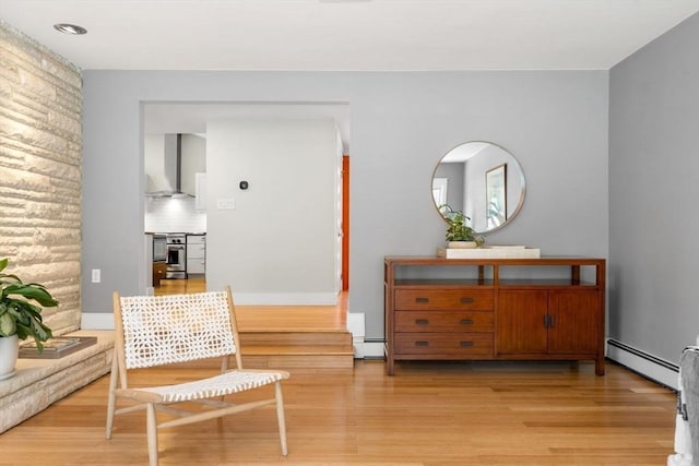 living area featuring a baseboard heating unit and light wood finished floors