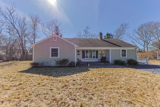 ranch-style home with a front lawn, fence, and a chimney