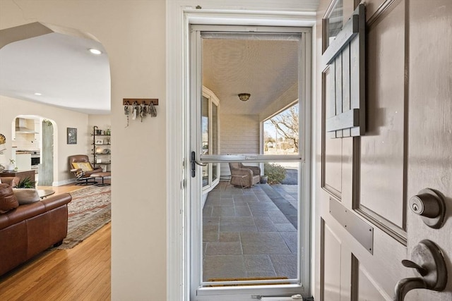 interior space featuring recessed lighting, baseboards, arched walkways, and stone tile floors