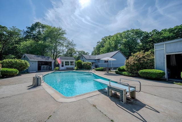 10 Primrose Rd, Billerica, MA 01821 - outdoor pool featuring a patio area, a diving board, a storage shed, and view of scattered trees