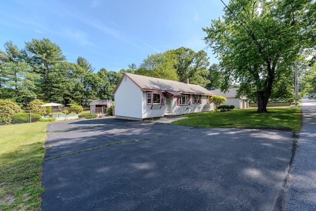 10 Primrose Rd, Billerica, MA 01821 - view of front of property with asphalt driveway, a front lawn, a pool, a chimney, and a storage unit
