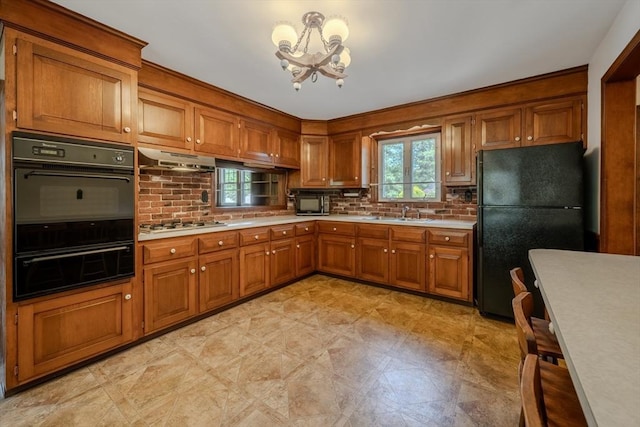 10 Primrose Rd, Billerica, MA 01821 - kitchen with black appliances, a warming drawer, brown cabinetry, and a chandelier