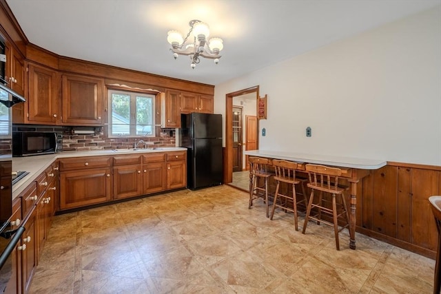 10 Primrose Rd, Billerica, MA 01821 - kitchen featuring black appliances, a chandelier, brown cabinets, light countertops, and a wainscoted wall