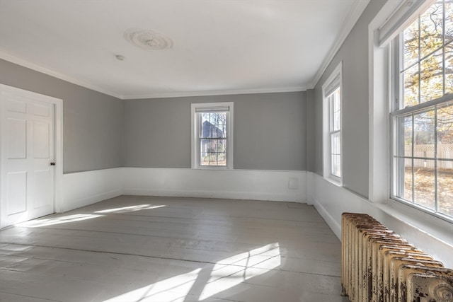 unfurnished room with radiator, ornamental molding, and light wood-type flooring