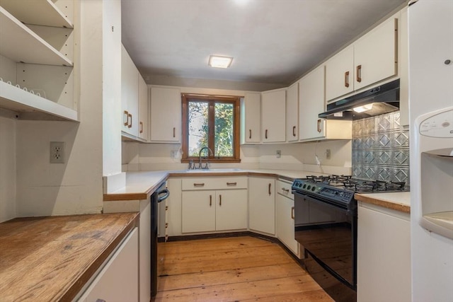 490 Plymouth, Bridgewater, MA 02324 - kitchen with black gas range, under cabinet range hood, white cabinetry, light wood-style floors, and backsplash