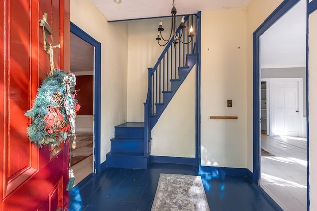 foyer entrance with crown molding and a notable chandelier