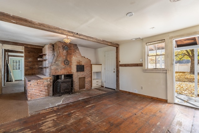 unfurnished living room featuring beamed ceiling, a wood stove, and dark hardwood / wood-style flooring