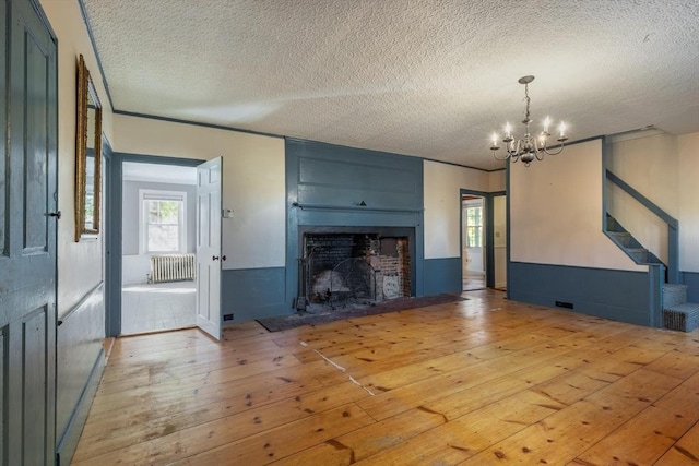 490 Plymouth, Bridgewater, MA 02324 - unfurnished living room featuring radiator, light wood-style floors, a chandelier, a textured ceiling, and a fireplace