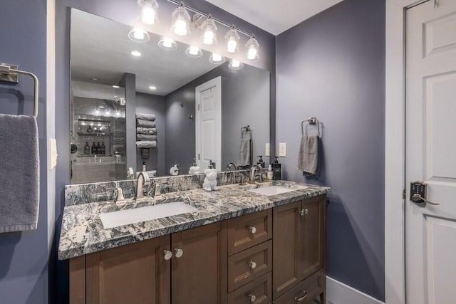 full bathroom featuring baseboards, double vanity, and a tile shower