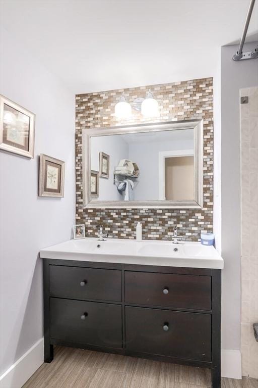 full bathroom featuring wood finished floors, double vanity, decorative backsplash, and baseboards