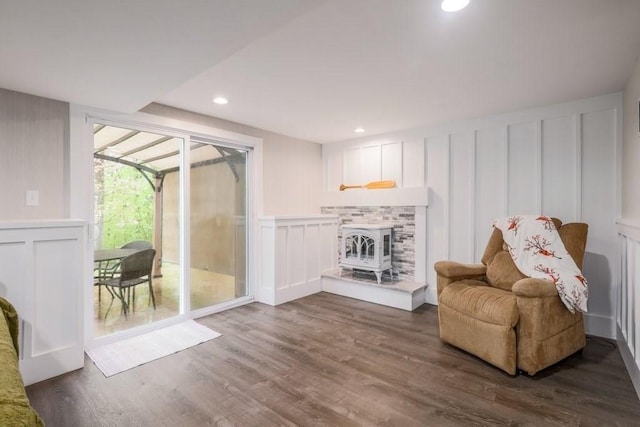 living area featuring a decorative wall, dark wood-type flooring, recessed lighting, and a wood stove