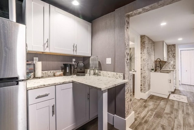 kitchen featuring freestanding refrigerator, light wood-style floors, white cabinets, light stone countertops, and recessed lighting