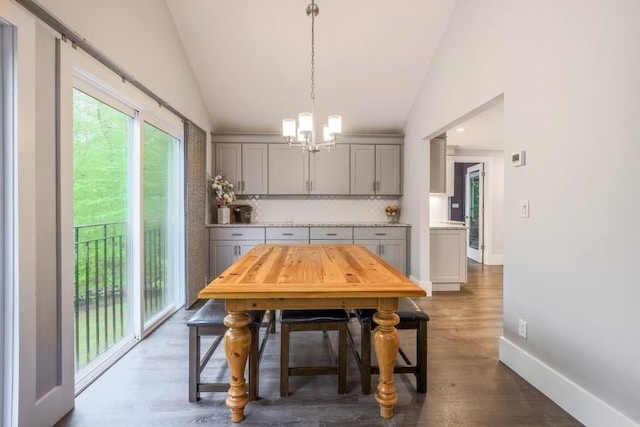 dining area with lofted ceiling, a chandelier, wood finished floors, and baseboards