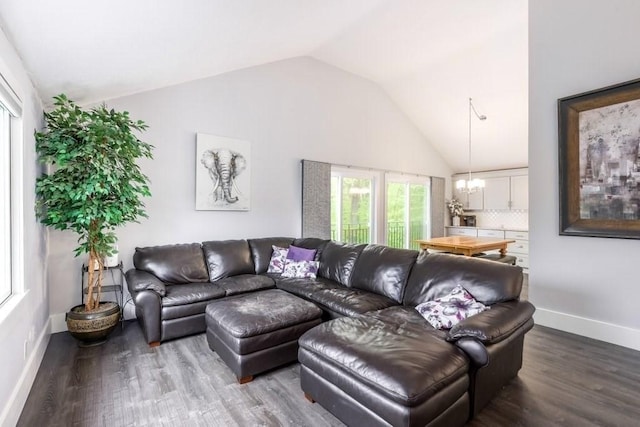 living area featuring vaulted ceiling, a chandelier, dark wood-style flooring, and baseboards