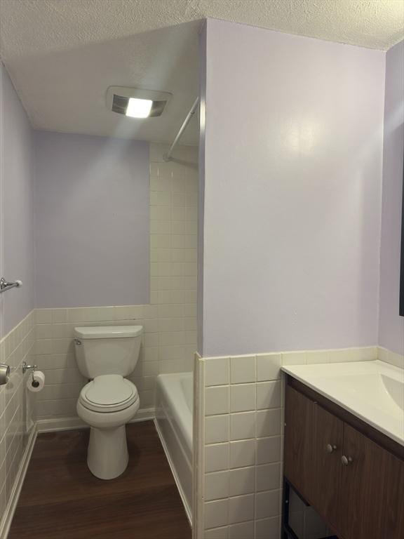 full bathroom featuring tile walls, a textured ceiling, and hardwood / wood-style floors