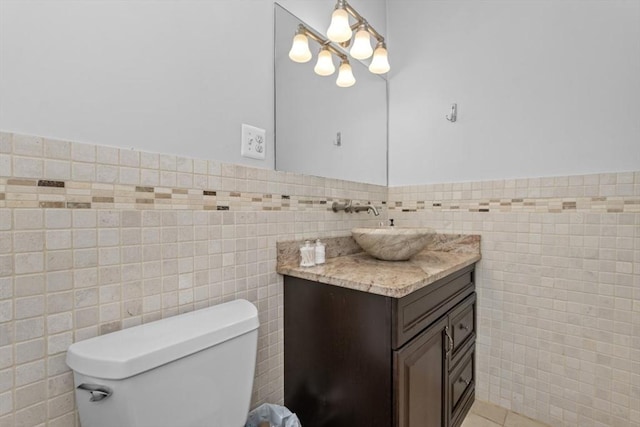 bathroom featuring tile walls, wainscoting, toilet, vanity, and tile patterned flooring