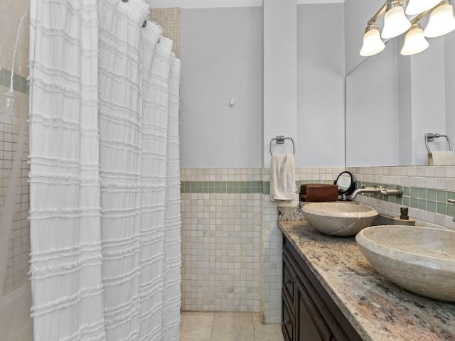 bathroom with tile walls, curtained shower, double vanity, and tile patterned floors
