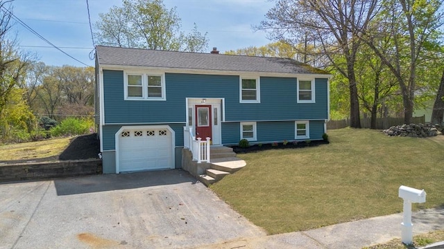 raised ranch with a garage, driveway, and a front lawn