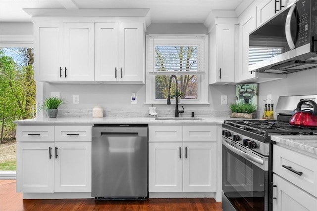 kitchen featuring a sink, appliances with stainless steel finishes, plenty of natural light, and white cabinetry