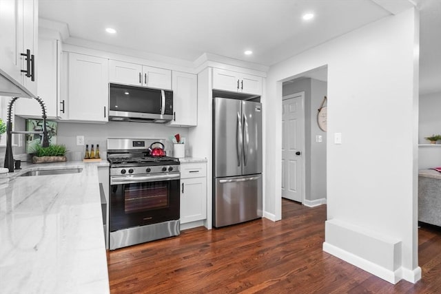 kitchen featuring appliances with stainless steel finishes, light stone countertops, recessed lighting, white cabinetry, and dark wood-type flooring