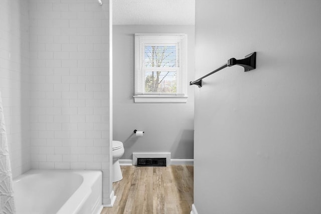 bathroom featuring visible vents, wood finished floors, shower / tub combo, baseboards, and toilet