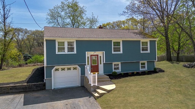 split foyer home with a garage, a front yard, and aphalt driveway