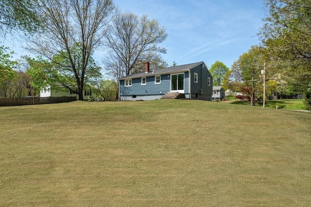 rear view of property with fence, a chimney, and a yard