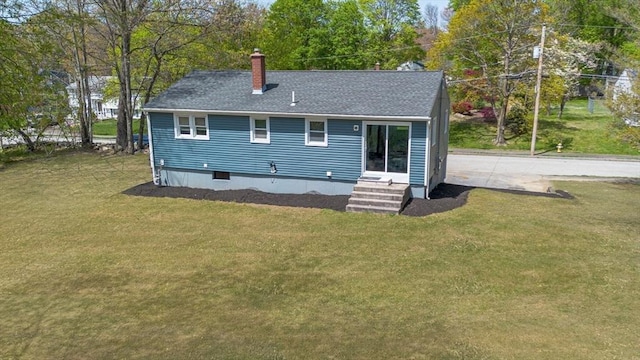 rear view of house featuring a lawn, a shingled roof, and a chimney