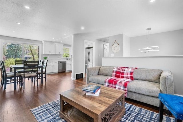 living area featuring dark wood-type flooring, recessed lighting, and a notable chandelier
