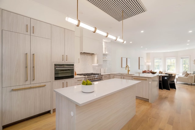 kitchen featuring light hardwood / wood-style floors, pendant lighting, sink, kitchen peninsula, and a center island