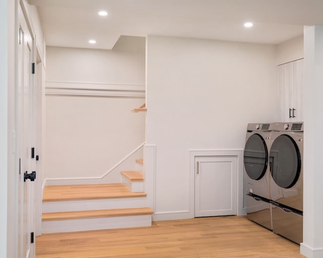 clothes washing area with light wood-type flooring and independent washer and dryer