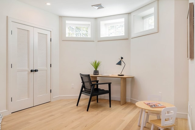 home office with a wealth of natural light and light hardwood / wood-style flooring