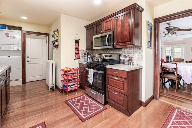 159 White St Unit 159, Belmont, MA 02478 - kitchen with gas range, stainless steel microwave, light countertops, estacked washer and dryer, and radiator heating unit