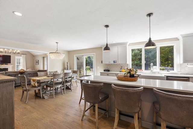 kitchen with pendant lighting, backsplash, light hardwood / wood-style flooring, and white cabinetry