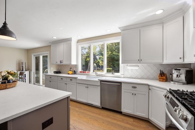 kitchen featuring decorative backsplash, stainless steel appliances, sink, decorative light fixtures, and light hardwood / wood-style floors