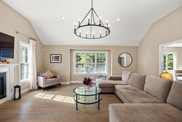 living room featuring hardwood / wood-style floors, vaulted ceiling, and a notable chandelier