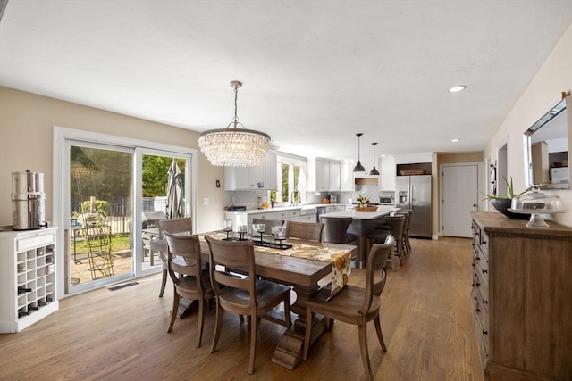 dining room featuring a notable chandelier, light hardwood / wood-style floors, sink, and a wealth of natural light