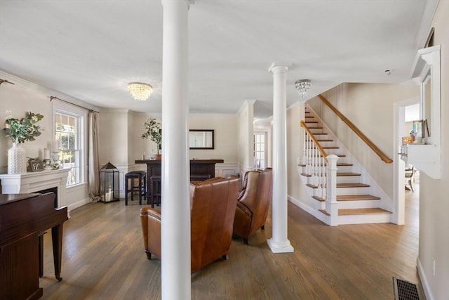 entrance foyer with ornate columns, crown molding, dark wood-type flooring, and an inviting chandelier