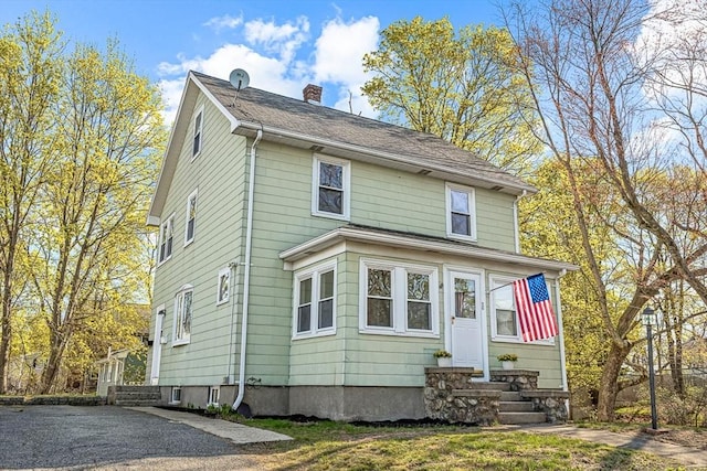 view of front facade with entry steps and a chimney