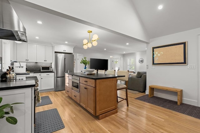 173 Liberty St, Braintree, MA 02184 - kitchen with range hood, stainless steel appliances, dark countertops, a kitchen breakfast bar, and light wood-type flooring