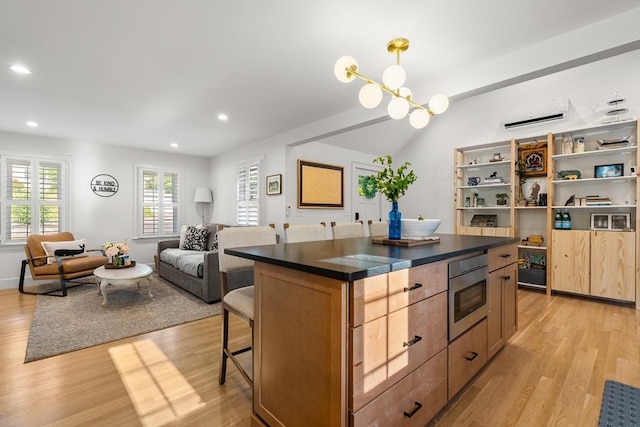 173 Liberty St, Braintree, MA 02184 - kitchen featuring dark countertops, light wood-style flooring, a kitchen breakfast bar, recessed lighting, and a wall mounted AC