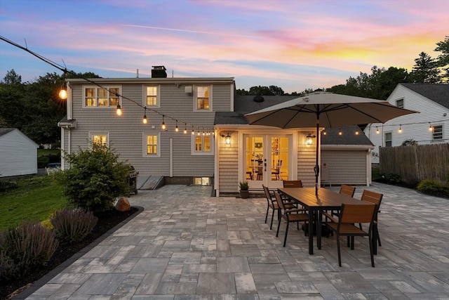 173 Liberty St, Braintree, MA 02184 - back of house at dusk with a patio area, outdoor dining area, a chimney, and french doors