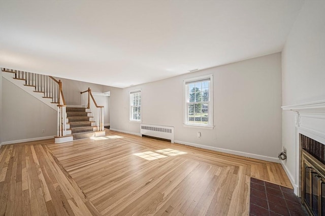 307 York St, Canton, MA 02021 - unfurnished living room with radiator, wood finished floors, baseboards, stairway, and a tile fireplace