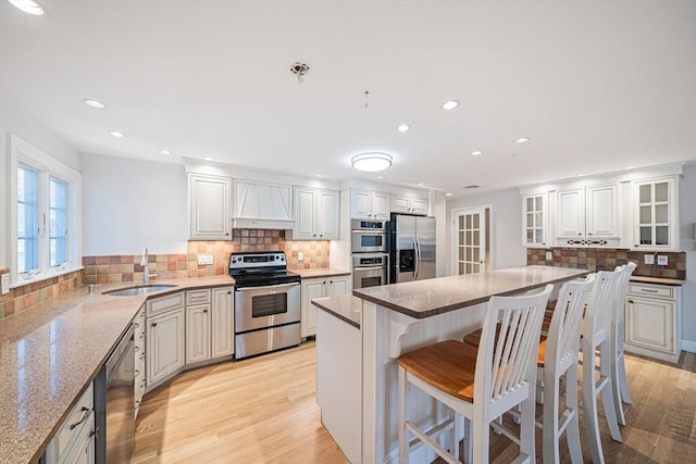 307 York St, Canton, MA 02021 - kitchen with a breakfast bar area, backsplash, a sink, premium range hood, and stainless steel appliances