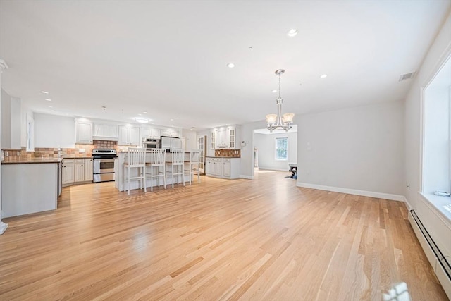 307 York St, Canton, MA 02021 - unfurnished living room with visible vents, baseboard heating, light wood-type flooring, a notable chandelier, and recessed lighting